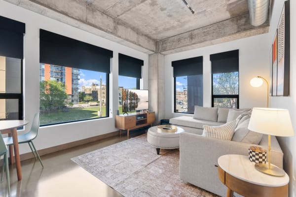 Modern living room featuring a gray sectional sofa, large windows, and a flat-screen TV.