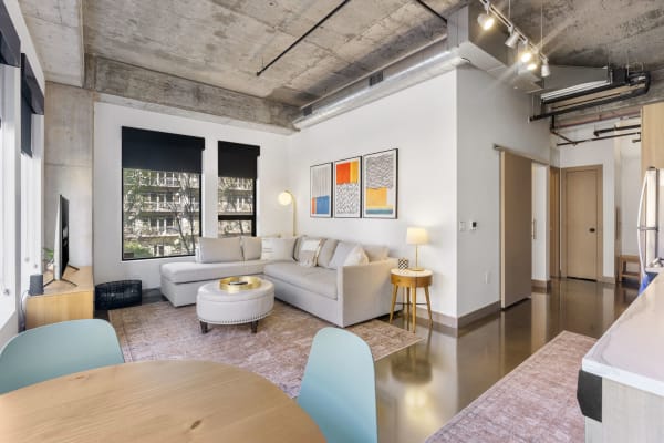 Stylish apartment interior with gray sectional sofa, decorative rug, and modern artwork.