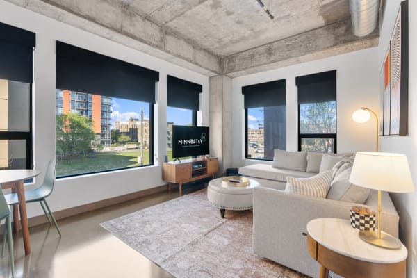 Stylish living room with a gray sectional sofa, coffee table, and large windows overlooking greenery.
