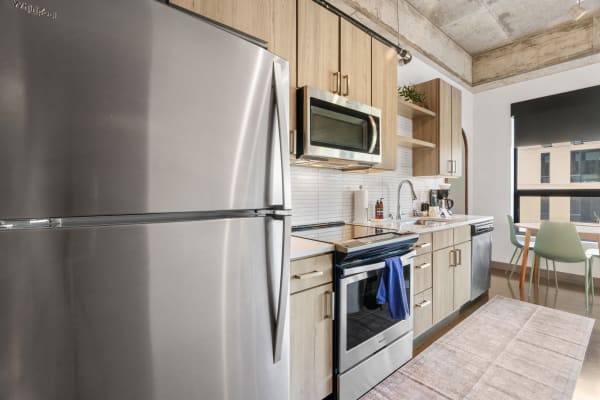 Modern kitchen with stainless steel refrigerator, microwave, and wooden cabinetry.