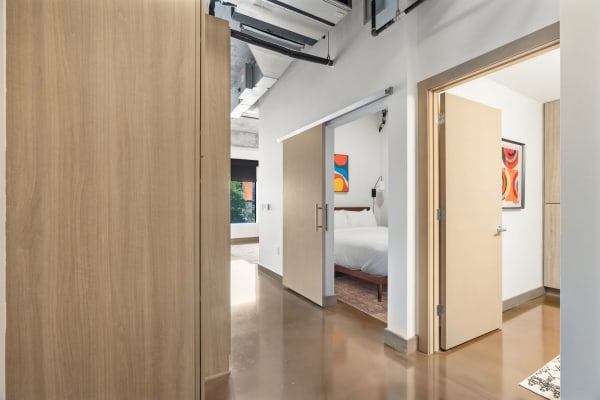 Interior hallway with wooden sliding door and artwork, opening to a bedroom.