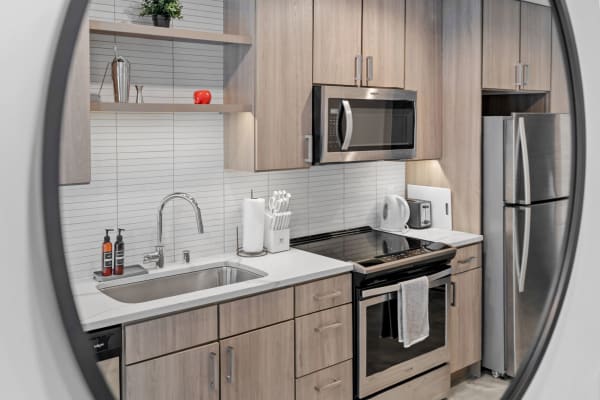 Modern kitchen featuring wood cabinets, stainless steel appliances, and stylish decor.