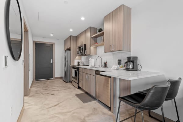 Interior view of a modern kitchen with light wood cabinets and stainless steel appliances.