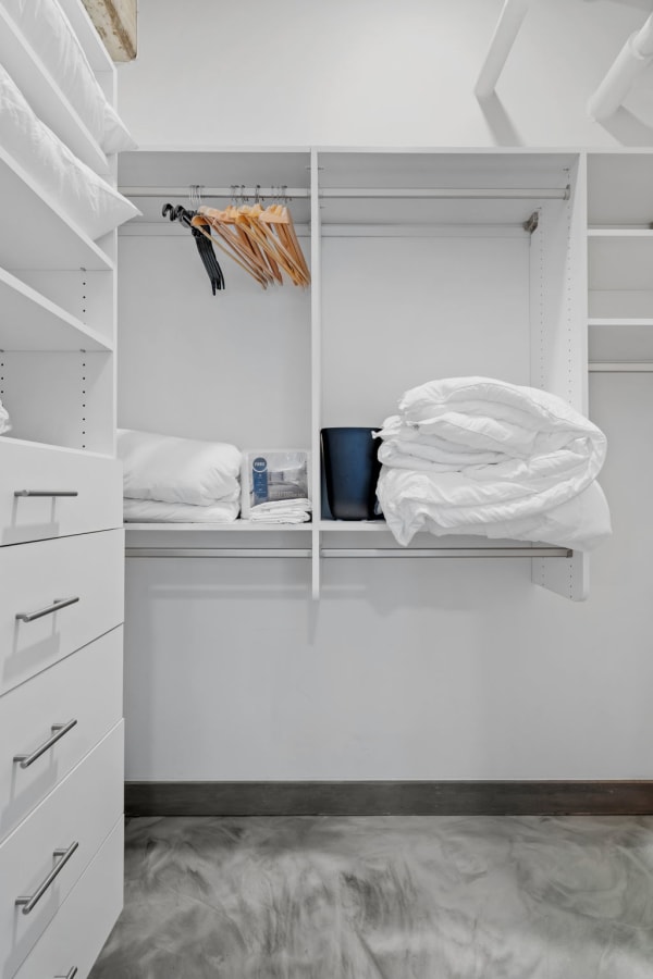 An organized closet with pillows, hangers, and a black storage bin.