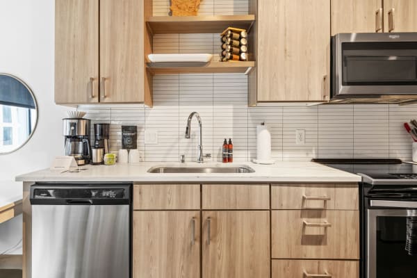 Contemporary kitchen with light wood cabinets, white countertop, and stainless appliances.
