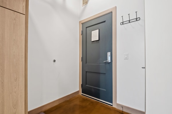 Contemporary entryway with a dark blue door and a coat rack.