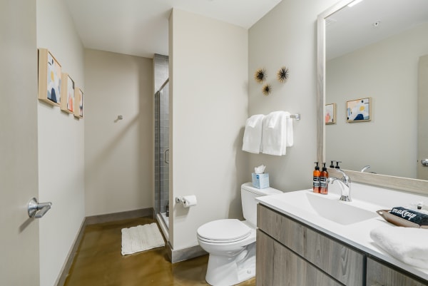 Interior view of a modern bathroom featuring a glass shower, wooden vanity, and decorative art.