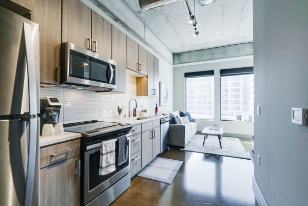 Modern kitchen with stainless steel appliances and a cozy living room with a gray sofa.