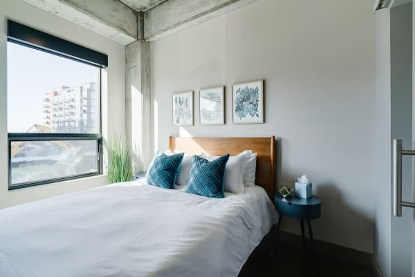 A bright bedroom with a wooden bed, accent pillows, and decorative wall art.