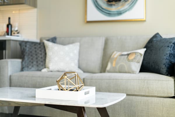 Elegant living room with a gray sofa, decorative pillows, and a geometric sculpture on a coffee table.