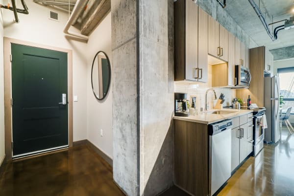 Modern kitchen and entryway with dark door and wooden cabinetry.