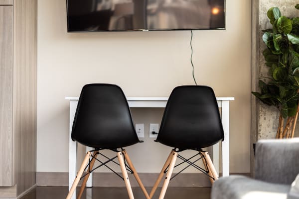 Two black chairs with wooden legs facing a white table in a modern home office setting.