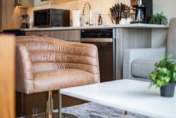 Cozy living room with a brown leather chair and modern kitchen in the background.