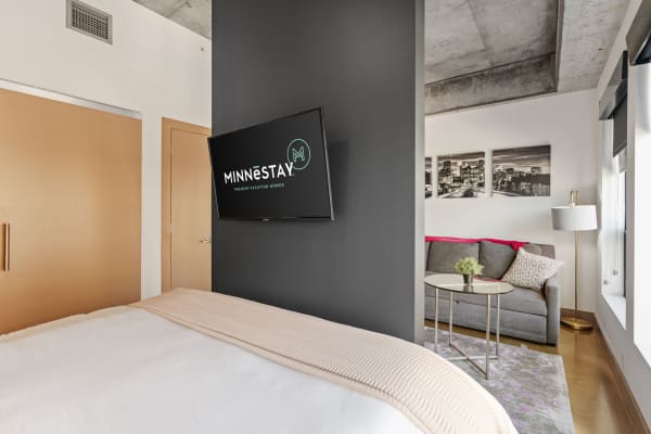 A stylish bedroom and living area in a vacation rental with a bed, TV, and sofa.
