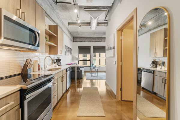 Interior view of a modern kitchen with stainless steel appliances and a cozy living area in the background.