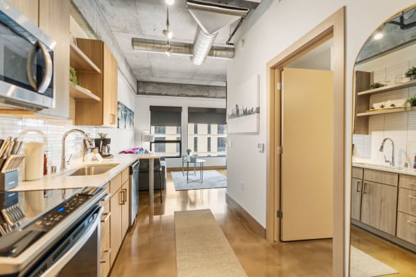 Contemporary kitchen and living area with wooden cabinets and stainless steel appliances.