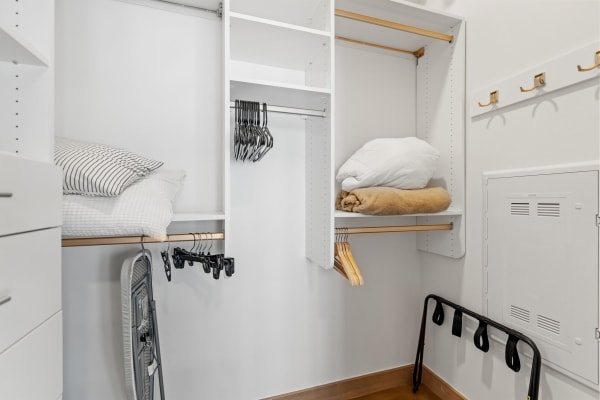 A minimalist closet with organized pillows and hangers.