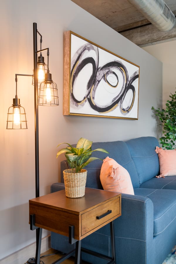 A modern living room with a blue sofa, decorative floor lamp, and abstract wall art.