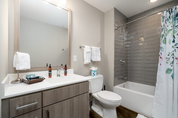 A contemporary bathroom featuring a white countertop, wooden cabinets, and a floral shower curtain.