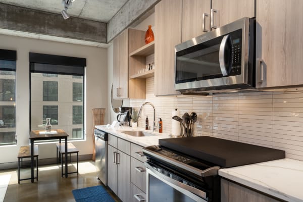 A stylish kitchen interior with wood cabinets, stainless steel appliances, and a dining area.