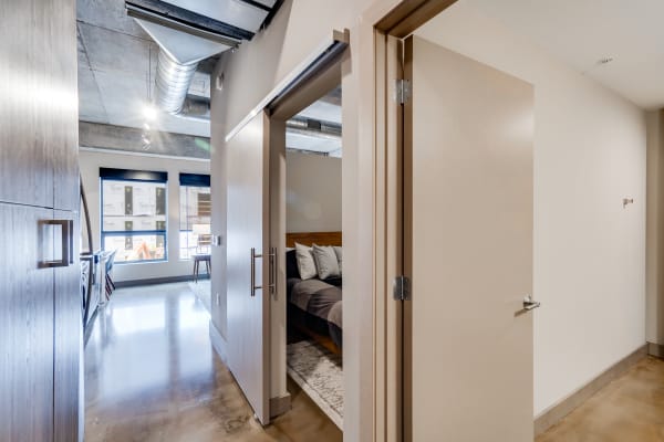 A hallway in a modern apartment with a view into a bedroom.