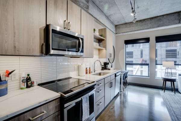 Contemporary kitchen with light wood cabinets and a stainless steel oven and microwave.