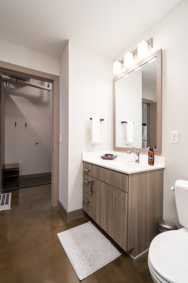 A stylish bathroom with a wooden vanity, white towels, and polished concrete floor.