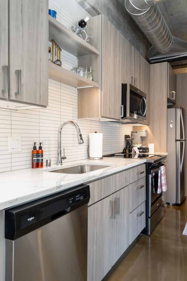 Modern kitchen with light gray wood cabinets and stainless steel appliances.
