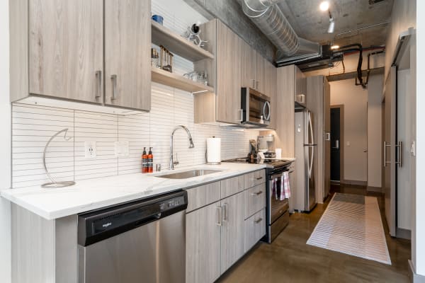 Modern kitchen featuring light gray cabinetry, stainless steel appliances, and a polished concrete floor.