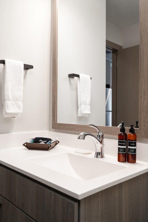 Contemporary bathroom counter with towels, soap, and lotion.