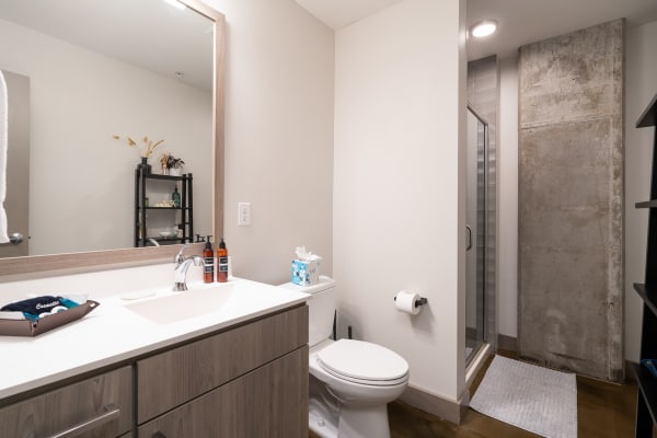 A clean and modern bathroom with a large mirror, contemporary sink, and shower.