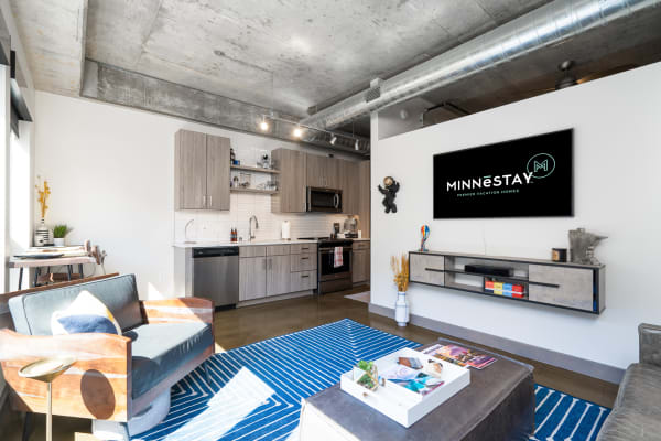 Stylish living area with kitchen, large windows, and modern furnishings.