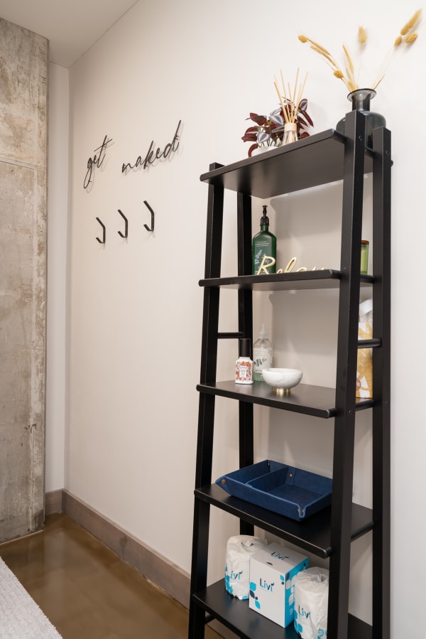 A modern bathroom corner with black ladder shelf, decorative items, and a clean aesthetic.
