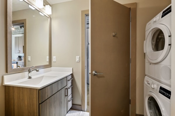 Contemporary bathroom with a wooden vanity and a stacked washer and dryer.