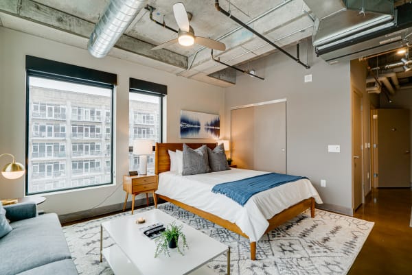 A contemporary bedroom with concrete ceiling, large windows, and a neatly made bed.