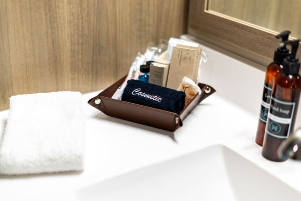 Organized bathroom countertop featuring a brown leather tray with cosmetics and a white towel.
