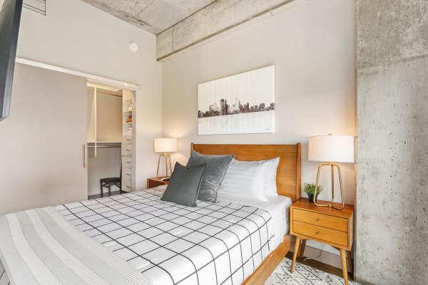 A contemporary bedroom with a wooden bed, geometric patterned blanket, and minimalist decor.