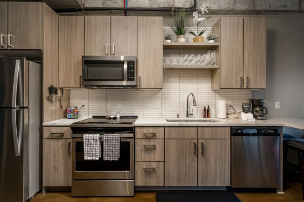 Contemporary kitchen featuring light wood cabinets, stainless steel appliances, and decorative plants.