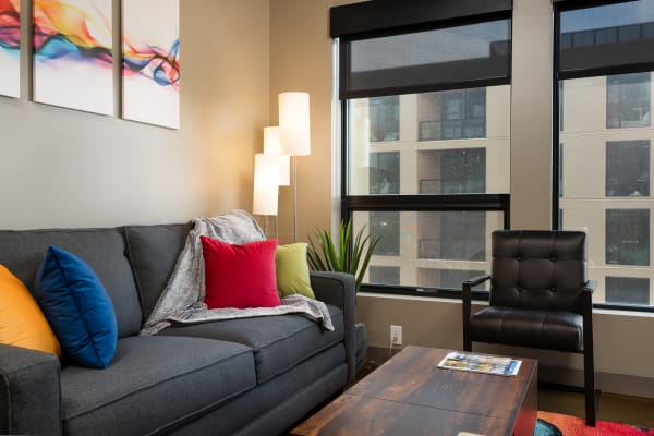 Cozy living room with a gray couch, colorful pillows, and a rainy outdoor view.