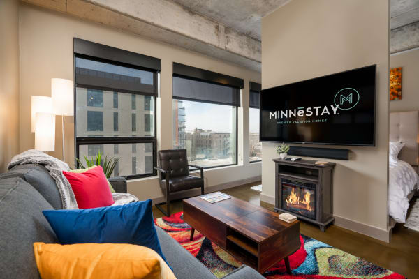Modern living room with colorful cushions, large windows, and a fireplace.
