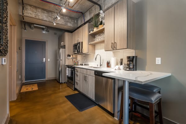 A contemporary kitchen featuring light wood cabinetry, a white countertop, and polished concrete flooring.