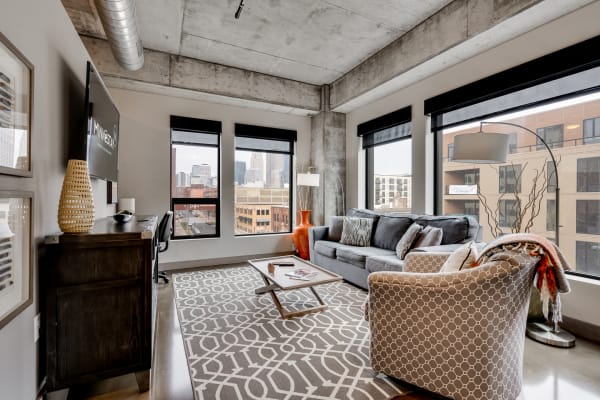 Modern living room featuring a gray sofa, armchair, coffee table, and city skyline views.