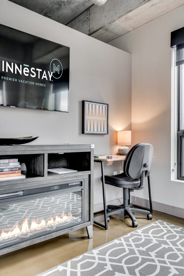 Modern vacation rental living space with a wall-mounted TV, workspace, and electric fireplace.