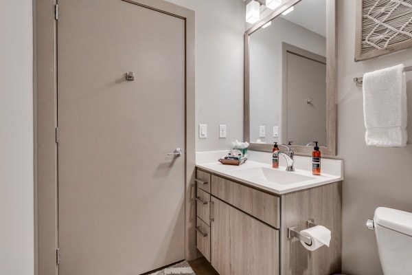 Modern bathroom featuring a light wood vanity with a white countertop and decorative details.