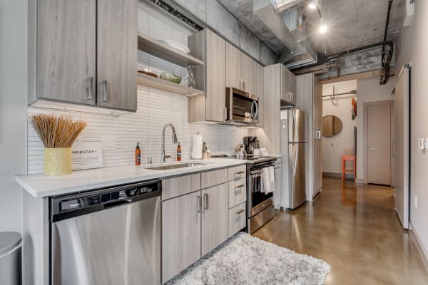 Modern kitchen featuring light wood cabinetry, stainless steel appliances, and a decorative vase on the countertop.