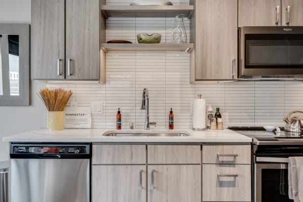 Modern kitchen with light wood cabinets, white countertop, and stainless steel appliances.