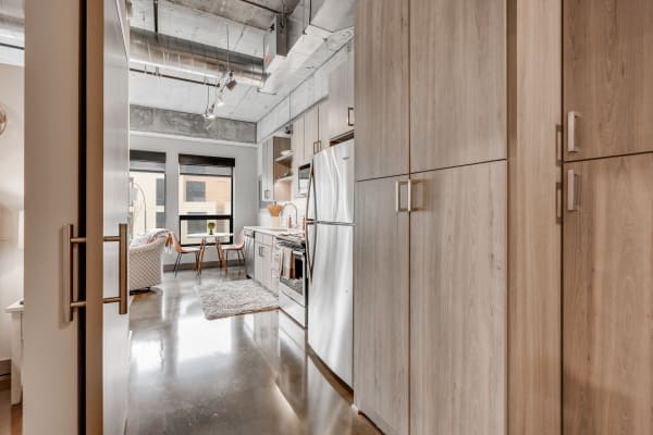 A contemporary kitchen interior featuring stainless steel appliances, light wood cabinetry, and a small dining table.
