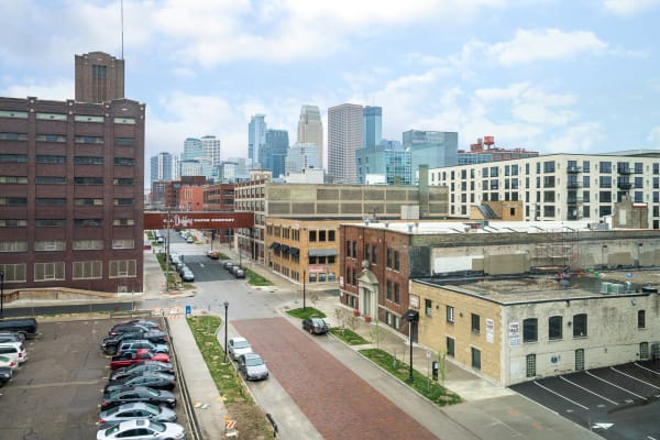 A cityscape showing a mixture of old industrial buildings and modern skyscrapers under a partly cloudy sky.