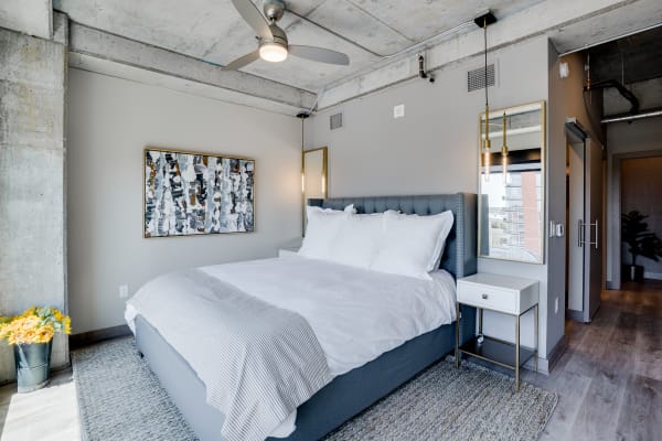 A stylish modern bedroom with a plush bed, abstract art, and a concrete ceiling.