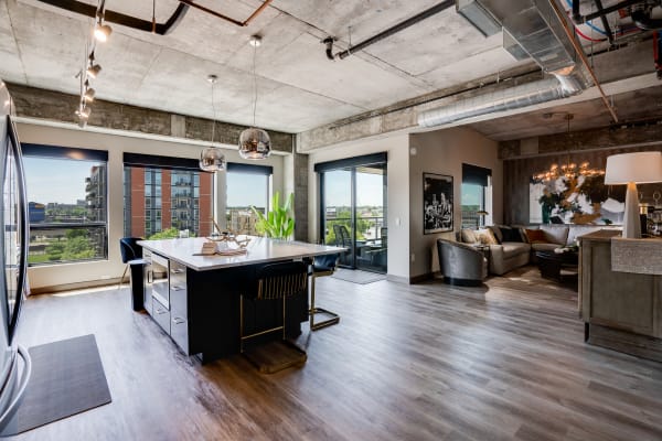 A contemporary kitchen and living area with large windows, stylish furniture, and an industrial design.